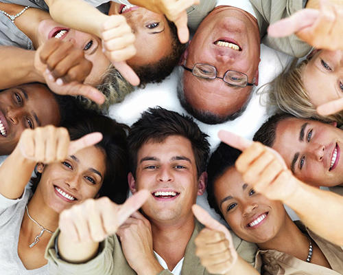 group of people laid in a circle on their backs smiling and giving a thumbs up sign